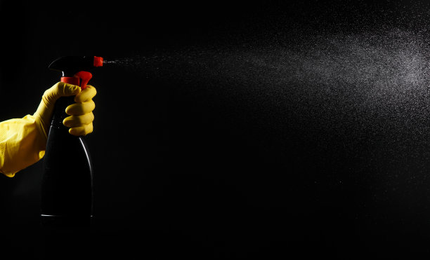 家用清洁剂，手上有黑色喷雾，戴着黄色橡胶手套图片下载