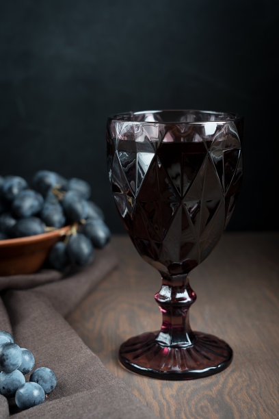 在厨房的深色木桌上，赤霞珠红葡萄酒和葡萄在陶碗里图片下载