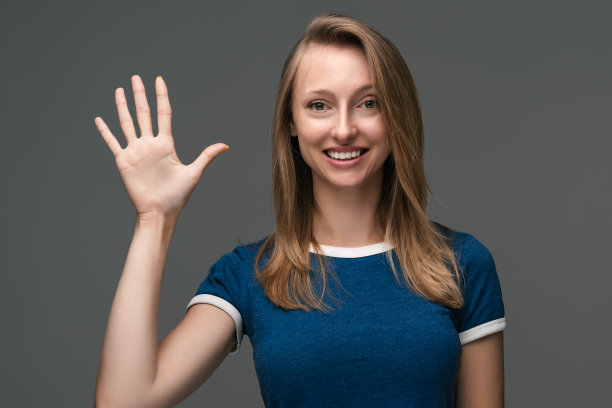 乐观的年轻金发女人在笑。工作室拍摄，灰色背景。人的情绪、表情概念图片下载