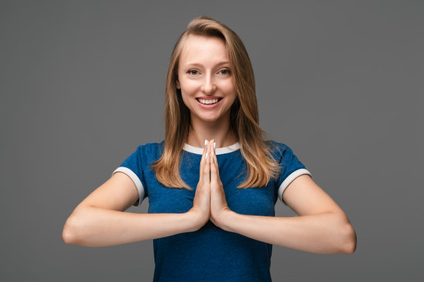美丽女孩的肖像看着相机和祈祷。工作室拍摄，灰色背景。放松的概念图片下载