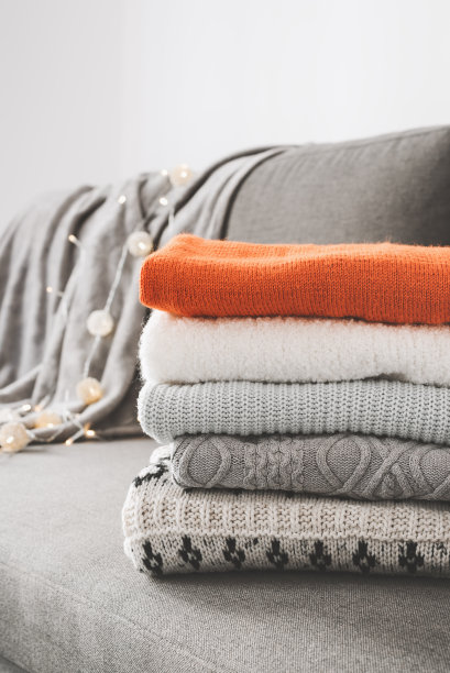 沙发床上灰色、白色和橙色的手工毛衣图片下载