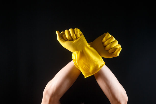 双手戴着黄色橡胶手套，背景为黑色图片下载