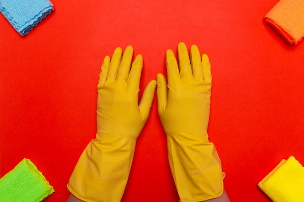 双手在黄色橡胶手套的中心围绕一块抹布在红色的背景图片下载