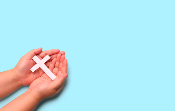 在工作室的蓝色背景上手持十字架十字架。图片下载