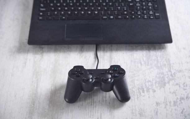 游戏控制器和笔记本电脑在白色的桌子上。图片下载