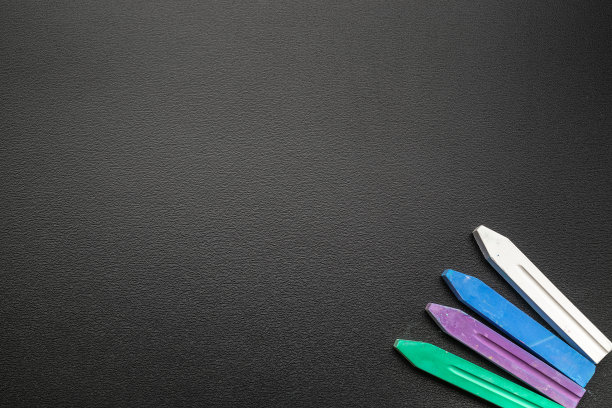 教育背景。学校文具用彩色的铅笔、粉笔、毛笔在教室的黑色黑板上。旗帜概念回到学校。图片下载