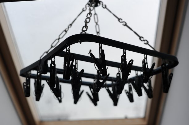 把衣架和夹子挂起来，晾干挂在屋顶窗户下的衣服，利用自然光图片下载