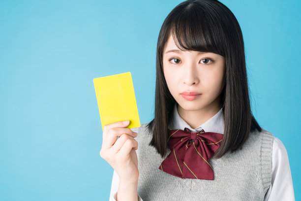 拿着黄牌的亚洲女学生。图片下载