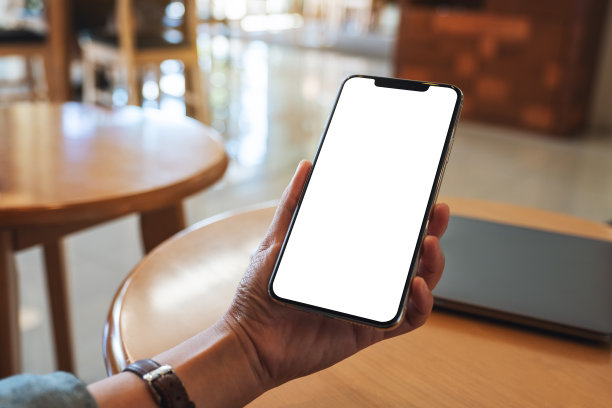 一个女人拿着手机和空白的桌面屏幕和笔记本电脑在桌子上图片下载