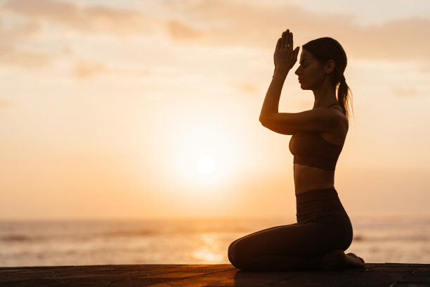 日落时在海滩上做瑜伽。在海里做体式，享受生活的女人图片下载