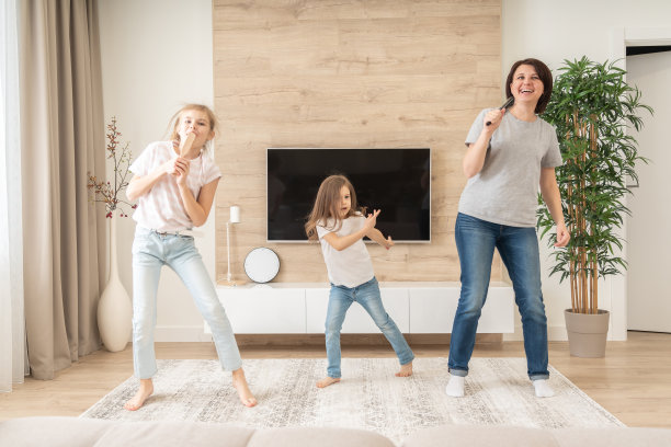 快乐的妈妈和两个女儿在发刷里唱卡拉ok。母亲笑着享受有趣的生活方式活动与十几岁的女孩在家里一起图片下载