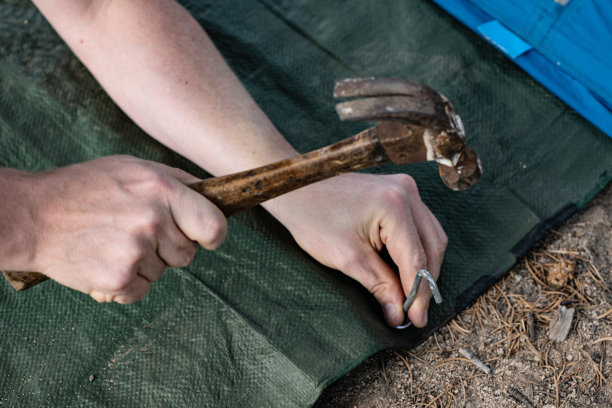 科罗拉多州露营地，一名白人男子用锤子将帐篷桩钉入地面图片下载