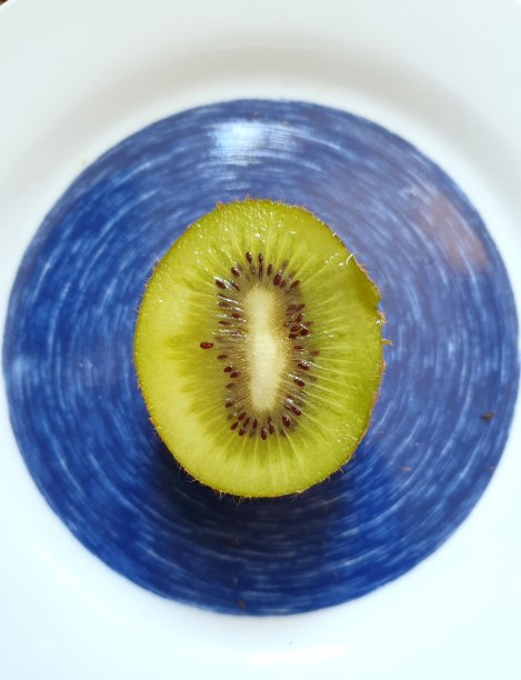 前视图。切猕猴桃细节。绿色的水果放在蓝色的盘子里假装眼睛。健康食物的背景主题，吃。全彩色图像。图片下载