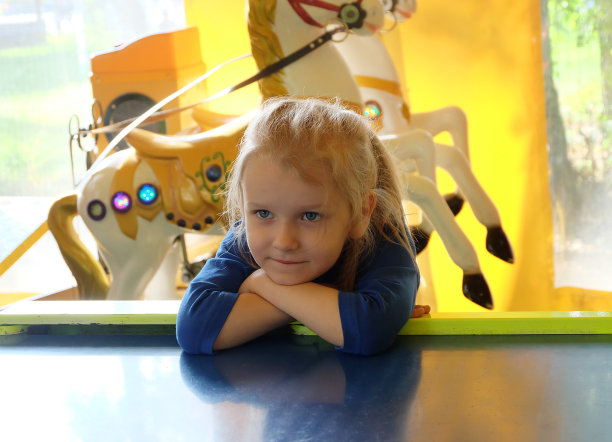 一个穿着蓝色裙子的五岁小女孩坐在一个游戏亭里。图片下载