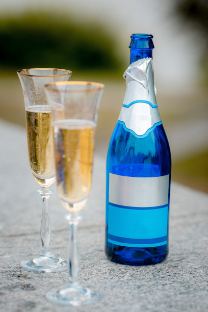 一瓶香槟和两个玻璃杯的特写照片。香槟在杯中摇曳。有选择性的重点。图片下载