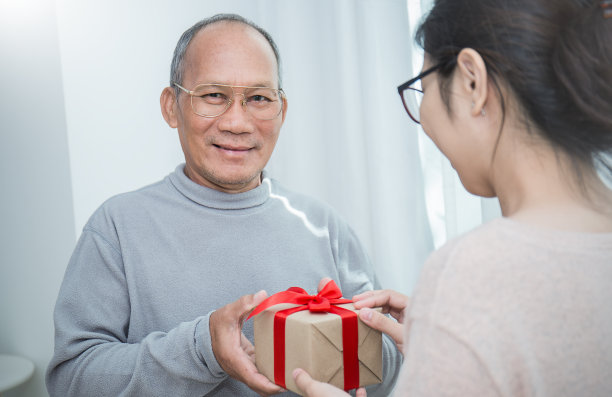 老人和他的女儿合拢双手赠送礼品盒。节礼日、生日、圣诞节概念图片下载