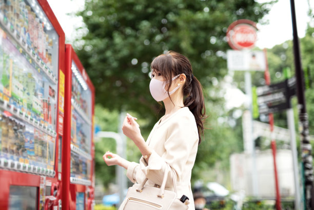 一个女人在街上用自动售货机买饮料图片下载