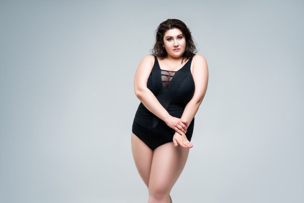 性感大码时装模特在黑色连体泳衣，女人在灰色的背景内衣图片下载