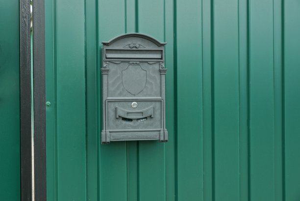 铁信箱挂在绿色的金属栅栏墙上图片下载