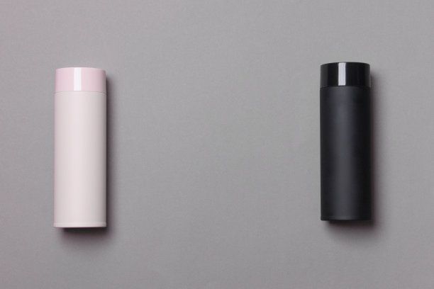 黑色和粉红色的热水瓶杯在灰色背景与复制空间图片下载