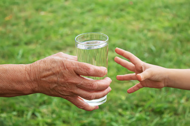 祖母给一个孩子一杯干净的水。有选择性的重点。图片下载