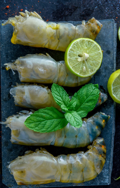 生虾放在木砧板上/鲜虾对虾在海鲜餐厅的深色背景上加香料，柠檬图片下载