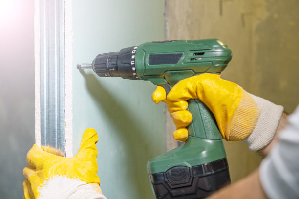 有干墙工作背景。工人手与钻螺丝干墙。图片下载