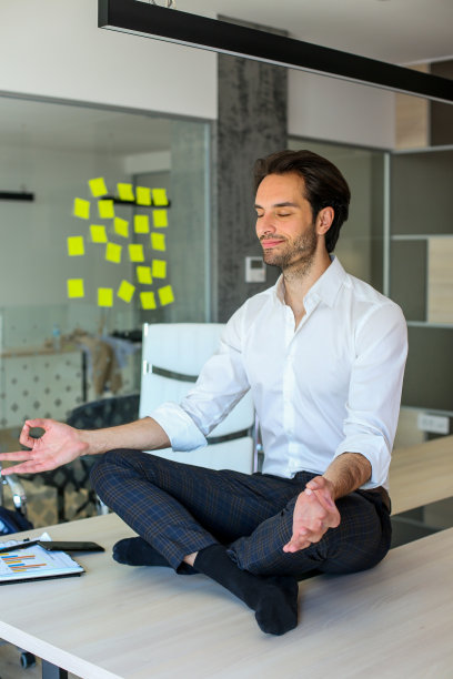 年轻有吸引力的商人坐在他的办公桌上，沉思和放松。图片下载