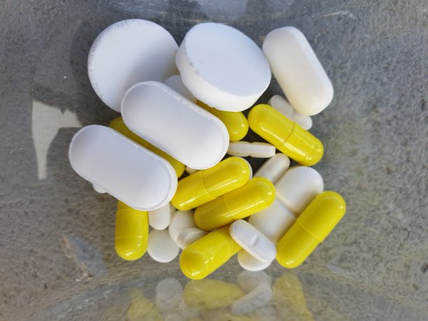 俯视图的玻璃瓶包含不同形状和颜色的药丸。背景纹理的药物，健康或药物成瘾的概念。图片下载