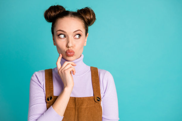 可爱的调情的女朋友的照片，女士决定创造浪漫的礼物，惊喜的男朋友看奇怪的空白手指下巴穿暖和的秋天装两个包子孤立的绿松石色背景图片下载