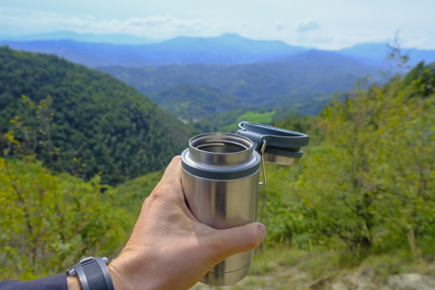 金属热杯在男人的手近距离跨越山脉景观。在山里徒步旅行。户外活动。本空间图片下载
