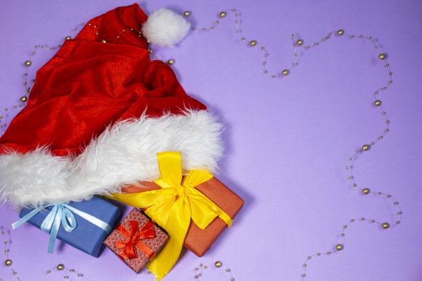 圣诞礼物和圣诞老人的帽子上五颜六色的背景。新年flatlay。图片下载