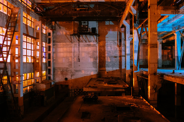 破旧的、空的、废弃的工业建筑内部，在夜晚图片下载