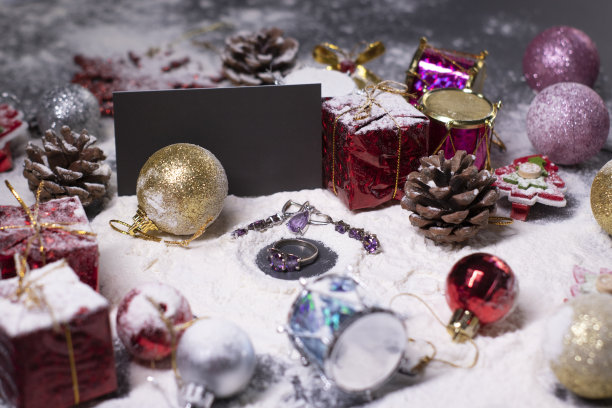 紫色的珠宝——戒指和耳环——旁边是雪地里的新年装饰品。圣诞树，球，雪花，礼物，蛋筒。圣诞节的心情。断然的照片图片下载