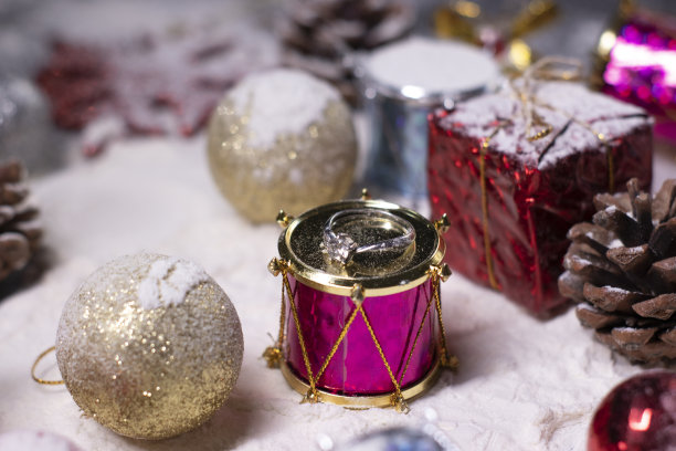 银质订婚戒指珠宝旁边的新年装饰品在雪中。圣诞树，球，雪花，礼物，蛋筒。圣诞节的心情。断然的照片图片下载