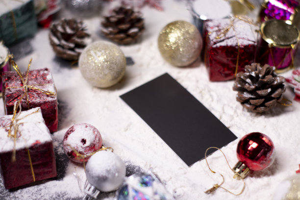黑色的名片旁边的新年装饰在雪中。圣诞树，雪花，礼物，松果。圣诞节的气氛图片下载