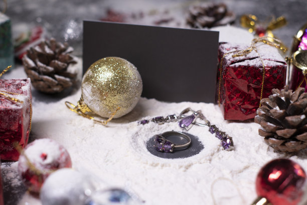 紫色的珠宝——戒指和耳环——旁边是雪地里的新年装饰品。圣诞树，球，雪花，礼物，蛋筒。圣诞节的心情。断然的照片图片下载