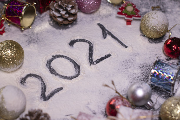 新年的装饰品，装饰元素——在雪中。圣诞树，球，雪花，礼物，蛋筒。在雪地里用手指画出“2021”。圣诞节的心情。断然的照片图片下载