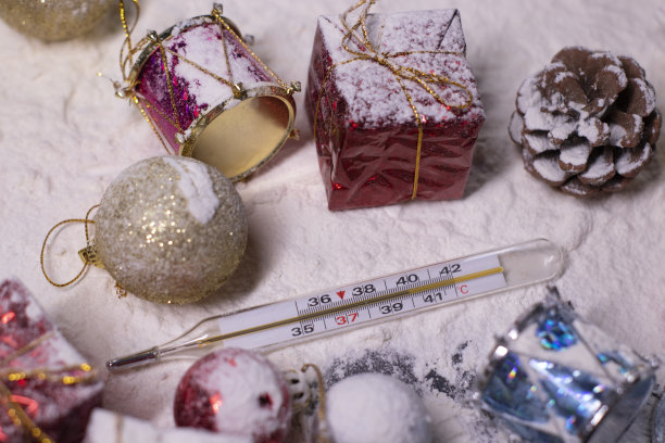 医疗体温计旁边的新年装饰品在雪地里。雪花,礼物,锥。圣诞节的心情。断然的照片图片下载