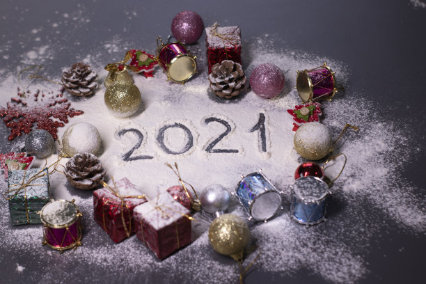 新年的装饰品，装饰元素——在雪中。圣诞树，球，雪花，礼物，蛋筒。在雪地里用手指画出“2021”。圣诞节的心情。断然的照片图片下载