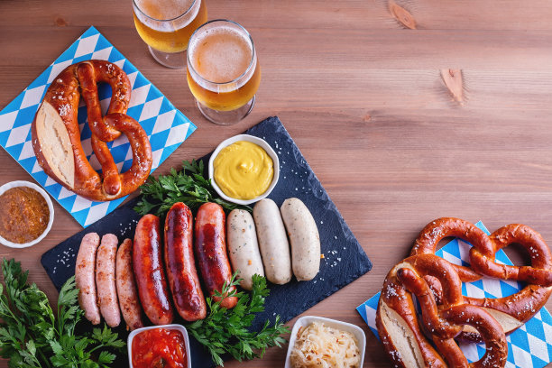 啤酒节餐桌上的传统食物。烤香肠，椒盐卷饼，啤酒，酸菜，芥末木背景，俯视图，拷贝空间，网络横幅图片下载
