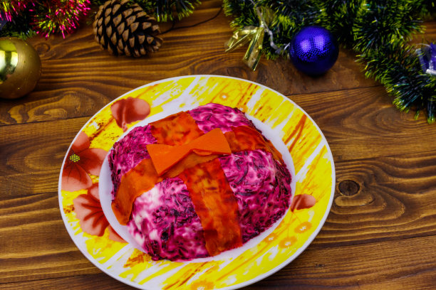 传统的俄罗斯沙拉“皮草下的鲱鱼”(舒巴)和木制桌子上的圣诞装饰品。做成礼品盒形状的沙拉图片下载