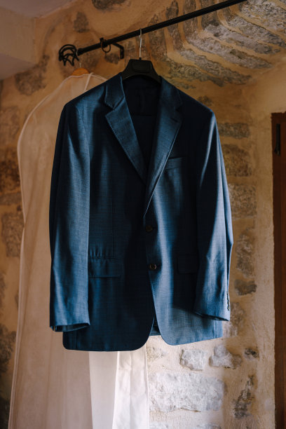新郎的蓝色夹克挂在黑色衣架上，房间里的衣服用白色的罩子遮盖。图片下载