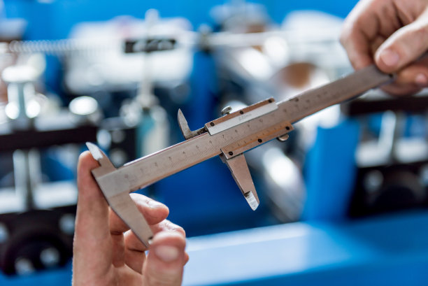 男性手拿游标卡尺测量钢环。图片下载