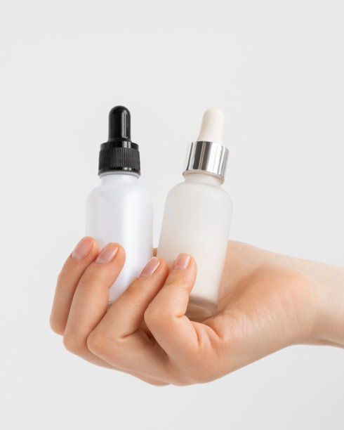 一个漂亮女人的双手捧着两瓶胶原蛋白精华保湿霜。图片下载