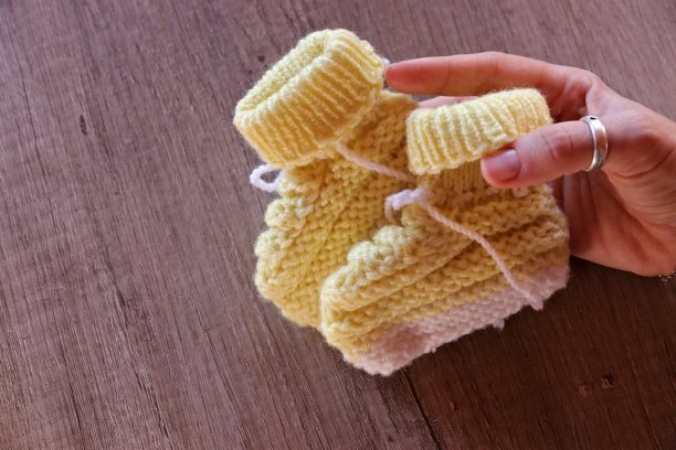 拿着自己制作的针织婴儿靴图片下载