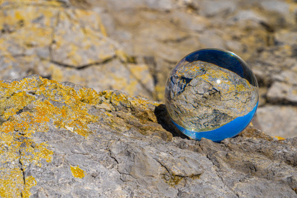 摄影水晶照片球显示颠倒的天空海滩和波浪平衡在岩石上的沙滩。图片下载