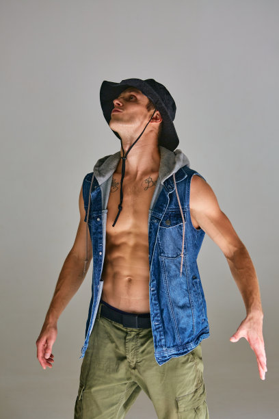 酷酷的年轻人与fit躯干和在巴拿马草帽站在工作室孤立的灰色背景图片下载