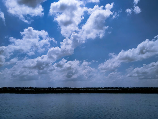 白云漂浮在蓝天上，营造出迷人的自然景色。图片下载