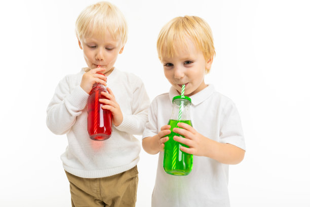 小男孩弟弟们有着浅红色的短发，蓝色的眼睛，可爱的外表，穿着白色的夹克，浅蓝色的裤子，站在镜头前摆出漂亮的姿势，拿着绿红相间的果汁装在玻璃瓶里图片下载
